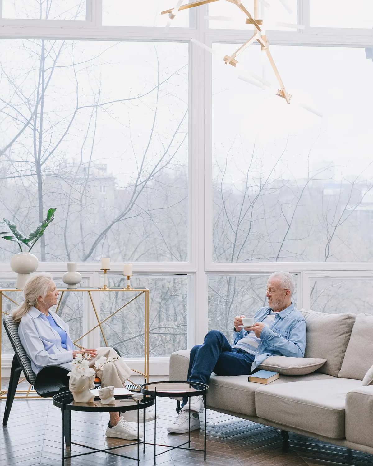 A senior couple sitting together in conversation in a bright, naturally lit living room